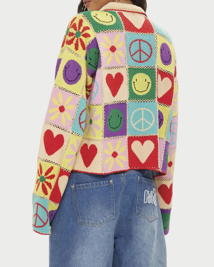 Person wearing a colorful patchwork sweater with various symbols on a white background
