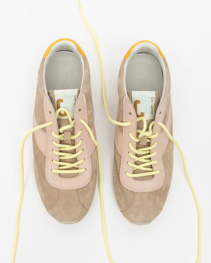Pair of beige sneakers with yellow laces on a white background
