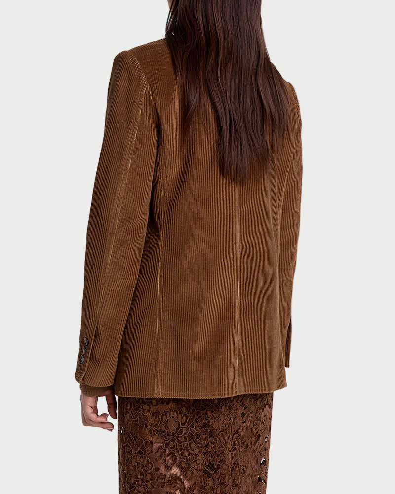 Person wearing a brown jacket and patterned pants on a white background