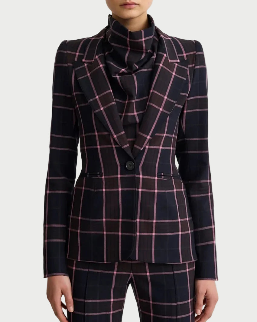 A model wearing a tailored navy windowpane plaid suit with pink lines, featuring a structured blazer with a high structured collar and matching trousers, set against a plain light gray background.