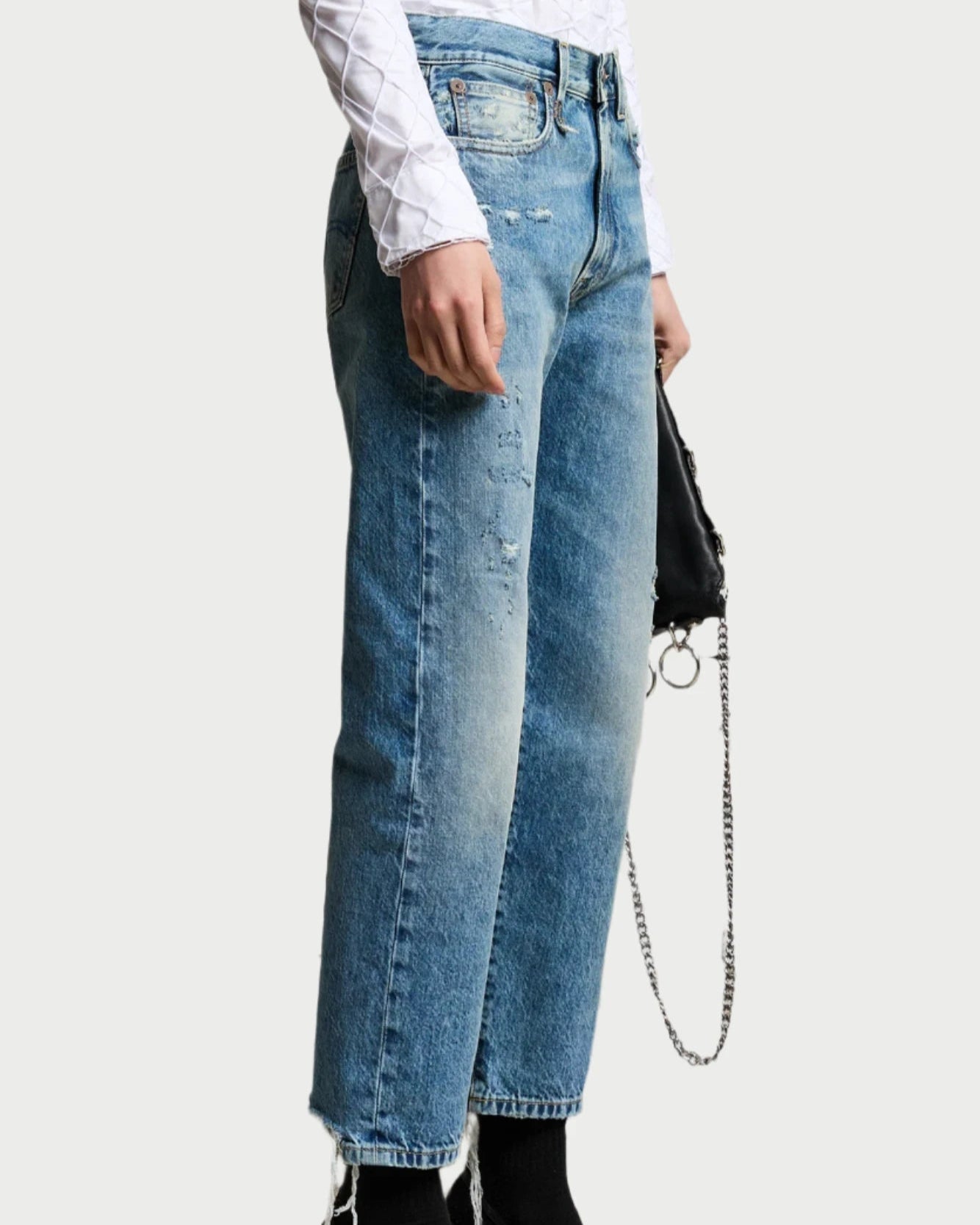 Person wearing blue jeans and black high-heeled shoes on a white background