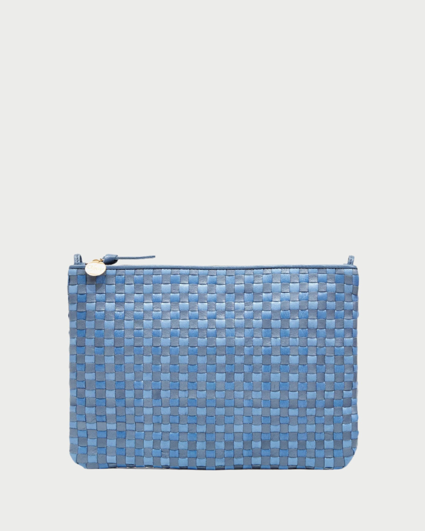 The CLARE V. Flat Clutch w/ Tabs is a versatile blue woven clutch featuring a basketweave texture on a white backdrop. Handwoven leather adds elegance, and it’s adorned with a small gold circular charm on the zipper.