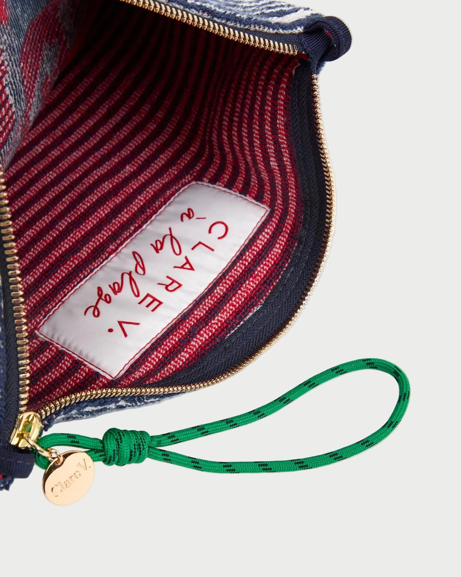 Close-up of a handbag with a visible brand label and green strap.