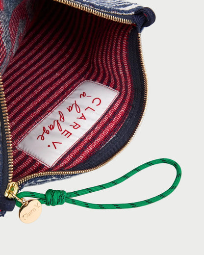 Close-up of a handbag with a visible brand label and green strap.