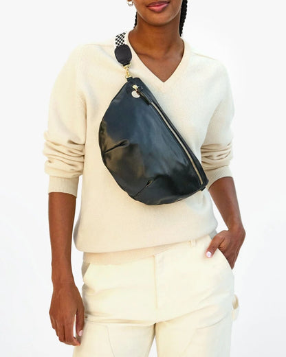 Person wearing a white sweater and pants with a black fanny pack on a white background