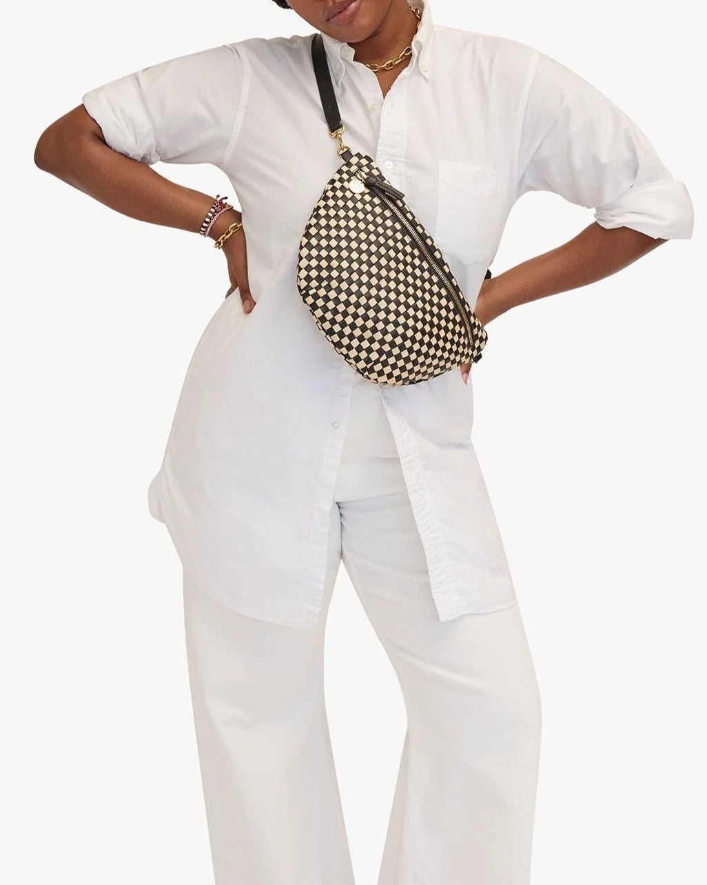 Person wearing a white outfit with a patterned bag on a white background