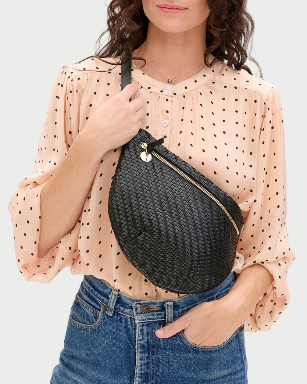 Woman holding a black woven bag against a white background