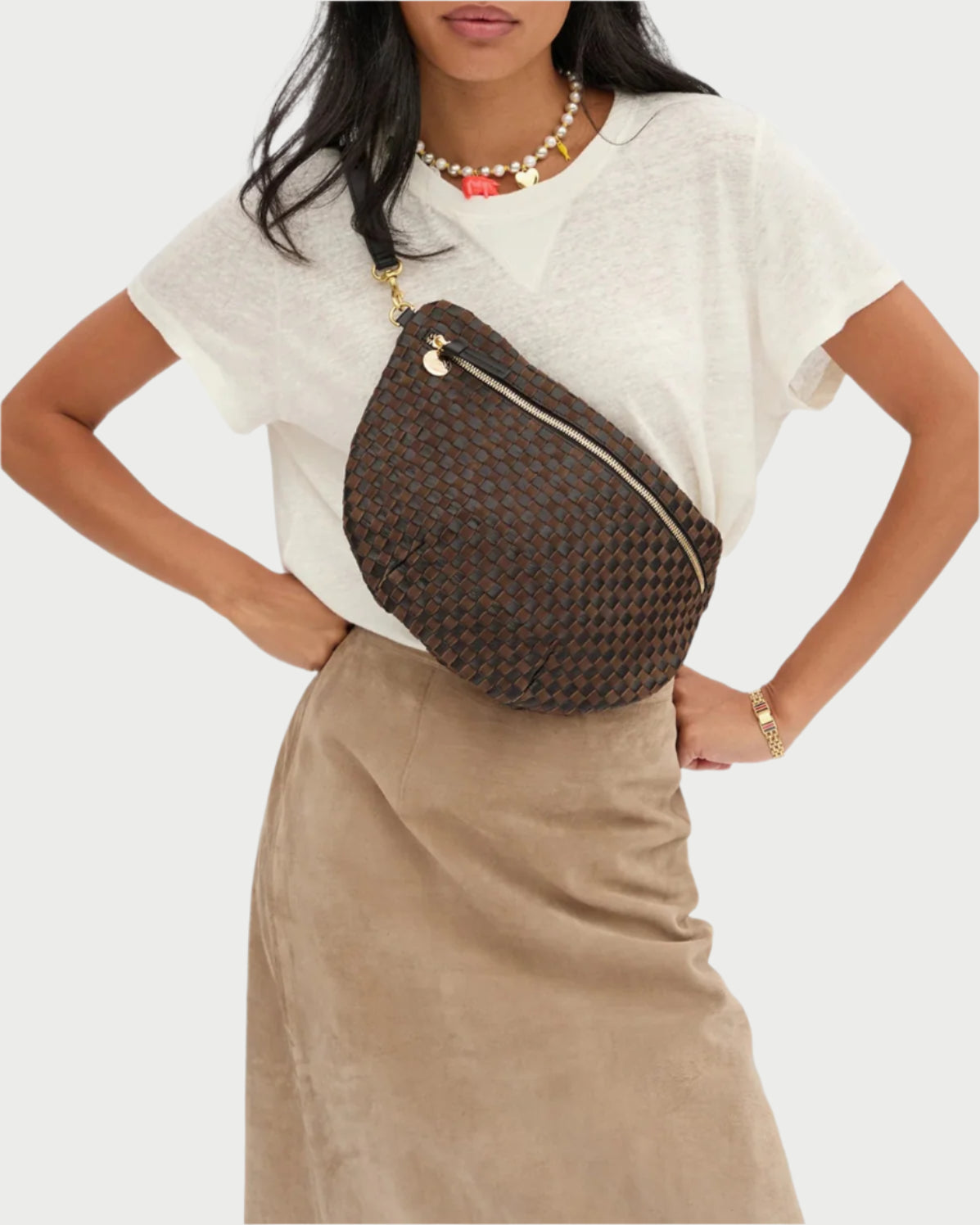 Woman wearing a brown woven crossbody bag on a white background