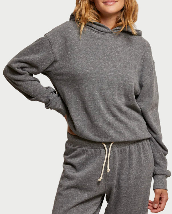 Woman wearing a gray hoodie and pants against a plain background