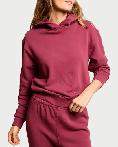 Woman wearing a maroon tracksuit against a plain background