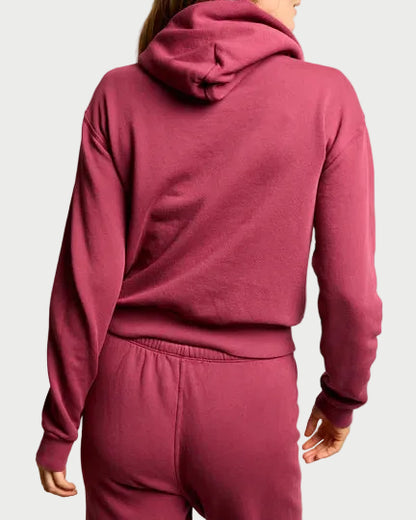 Person wearing a maroon tracksuit against a plain background