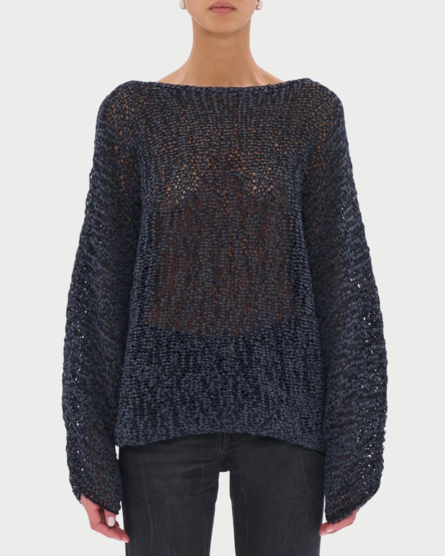 Person wearing a dark textured sweater and sunglasses on a light gray background