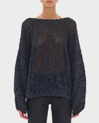 Person wearing a dark textured sweater and sunglasses on a light gray background