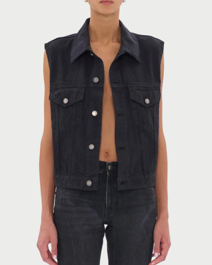 Person wearing a black sleeveless denim vest on a white background