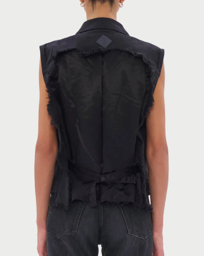 Person wearing a black sleeveless denim vest on a white background