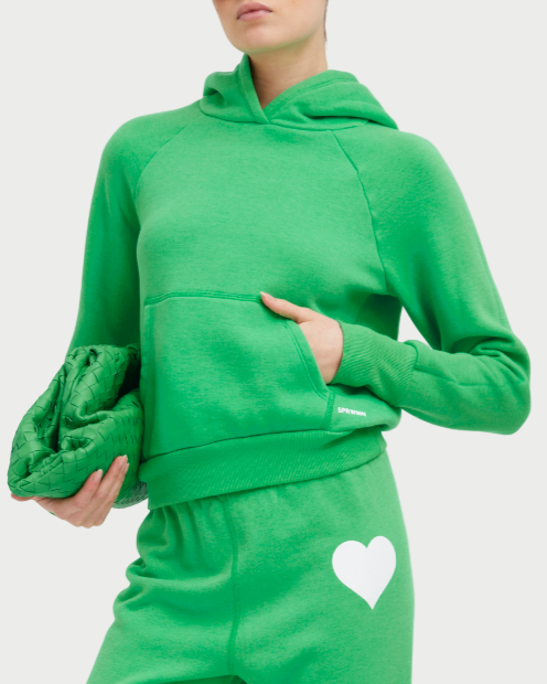 Person wearing a green hoodie and pants with a heart design on a white background