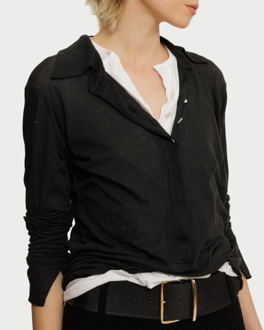 Woman wearing a black jacket over a white shirt on a plain background
