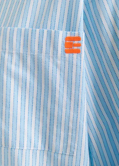 Close-up of the Essentiel Antwerp Double Cuff Shirt’s light blue and white striped cotton pocket, with three short orange embroidered lines at the top right corner.