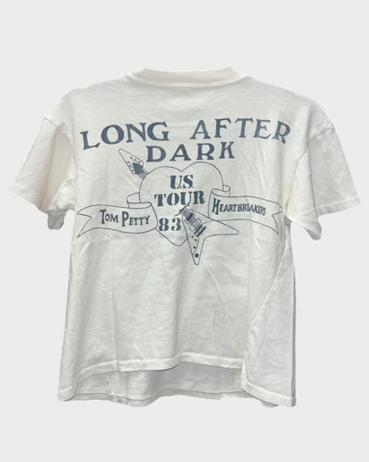 Explore the Madeworn Tom Petty Tee, crafted from 100% white cotton with a vintage fit. It showcases the "Long After Dark" US Tour '83 design, featuring an electric guitar graphic and a banner with "Tom Petty" and "Heartbreakers.