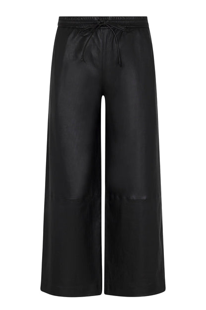 SPRWMN Cropped Leather Baggy Pants by SPRWMN are black wide-leg track pants with a shiny finish, drawstring waistband, relaxed fit, and a sleek, modern look—no visible pockets or embellishments.