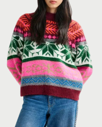 Woman wearing a colorful patterned sweater and jeans on a white background
