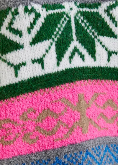 Close-up of the Essentiel Antwerp Jacquard Sweater by Essentiel Antwerp, showcasing green and white leaf motifs, pink and beige geometric patterns, and blue-gray mélange knit sections.
