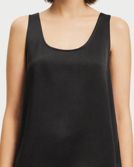 A woman models the Saint Art Isola Black Scoop Neck Tank by Saint Art NY, shown from shoulders to waist against a plain white background. Her face is not visible, emphasizing this versatile minimalist wardrobe essential.