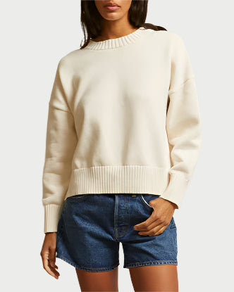 A woman in the perfectwhitetee Janet Ivory Cotton Sweater and blue denim shorts stands against a plain light background, her face partially out of frame.