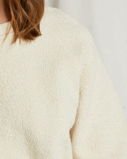 Close-up of a textured beige sweater with a blurred background