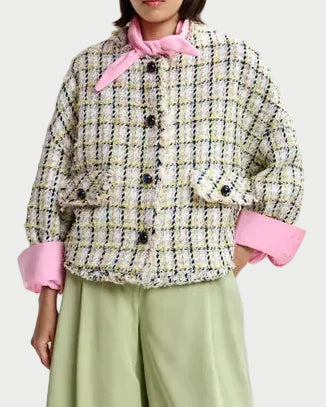 Person wearing a patterned jacket with pink accents and light green pants on a white background