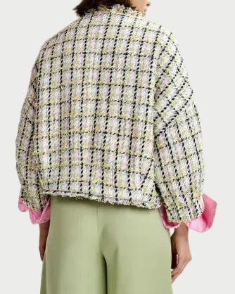 Person wearing a plaid jacket with pink cuffs and green pants on a white background