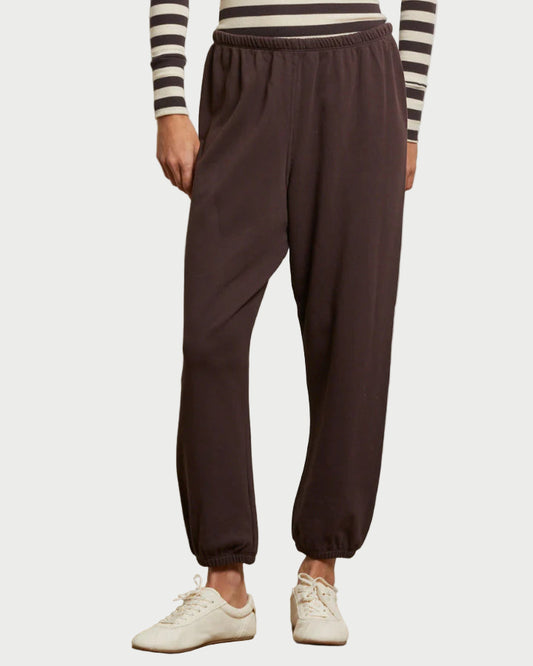 Person wearing brown sweatpants and a striped shirt on a white background