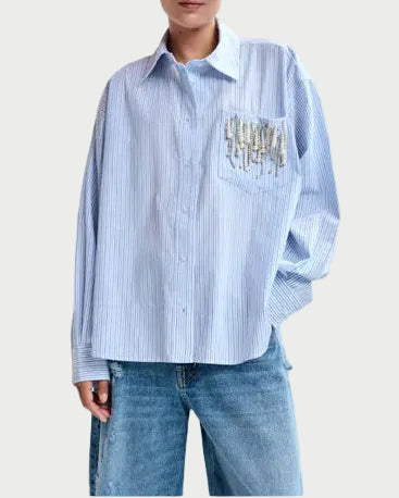 Woman wearing a blue striped shirt with a pocket design on a light gray background