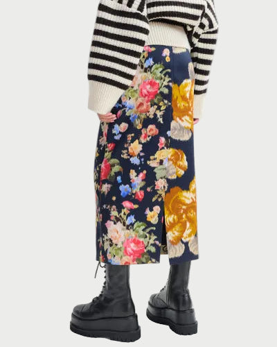 Person wearing a black and white striped sweater, floral skirt, and black boots on a white background