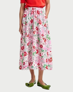 Woman wearing a red blouse and floral skirt on a white background