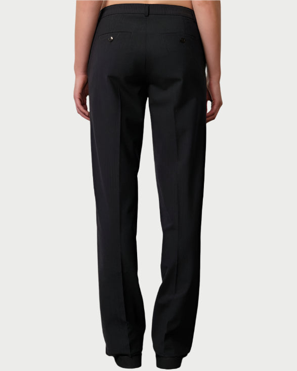 Person wearing black lace top and black pants on a plain background