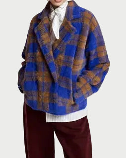 A person wearing the Essentiel Antwerp Karreau Check Cardigan Jacket—featuring a loose blue and brown plaid design—over a white shirt and maroon pants, standing against a light background.