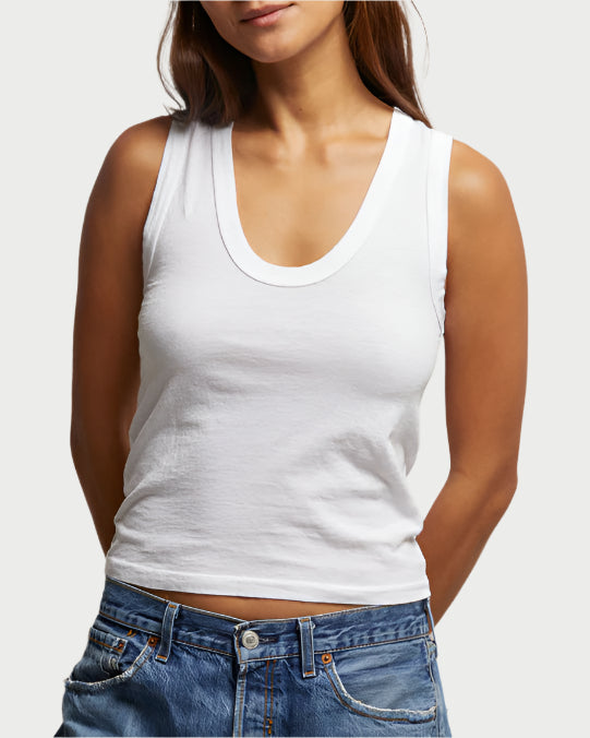 Wearing the Khara Scoop Tank by perfectwhitetee and blue jeans, a person stands with hands behind their back against a plain light background.