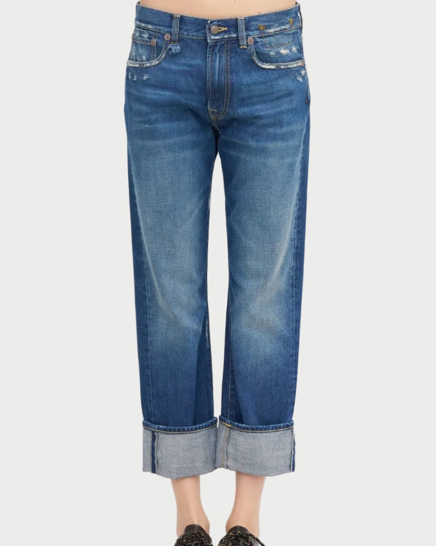 A person wearing R13 Cuffed Romeo Jean Oasis Blue—slim boyfriend fit, lightly distressed Italian denim—stands against a white background.