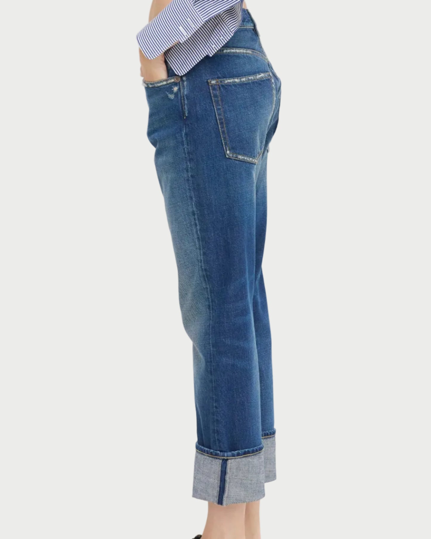 A person wears R13 Cuffed Romeo Jean Oasis Blue in a slim boyfriend fit with a blue-and-white striped shirt, shown from the side against a white background.