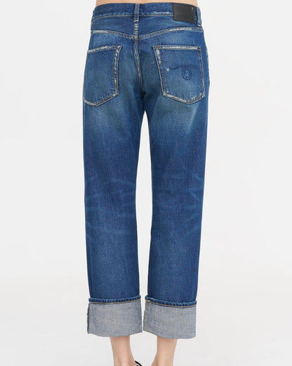A person is seen from the back wearing the R13 Cuffed Romeo Jean in Oasis Blue, featuring a slim boyfriend fit, Italian denim, cuffed hems above the ankles, two faded back pockets, and a black patch on the cropped waistband.