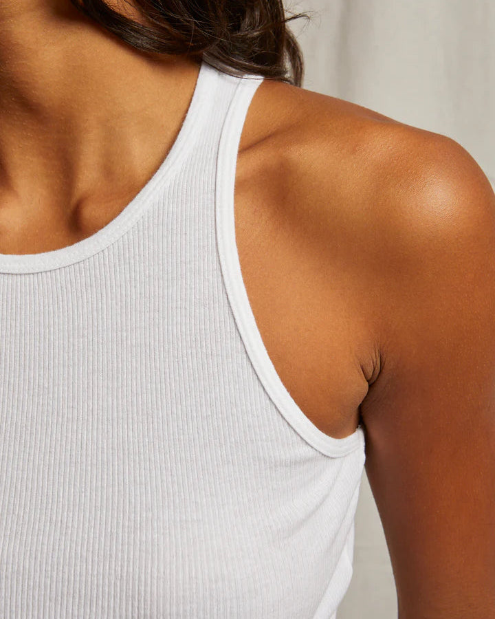 A close-up of a person wearing the Kravitz Rib Tank by perfectwhitetee, highlighting their shoulder, collarbone, and part of their arm against a neutral background.