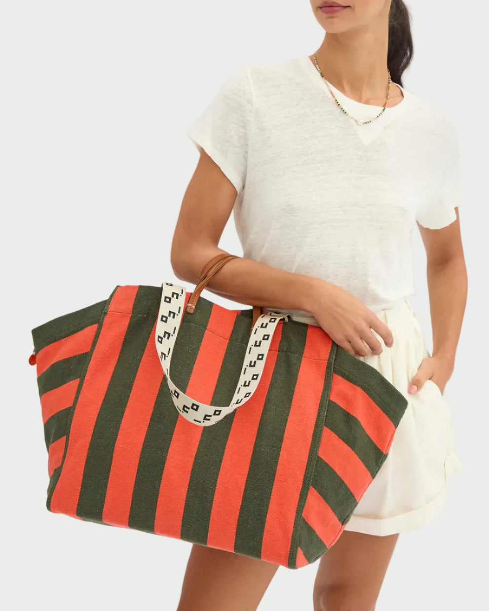 Woman holding a red and green striped bag on a white background
