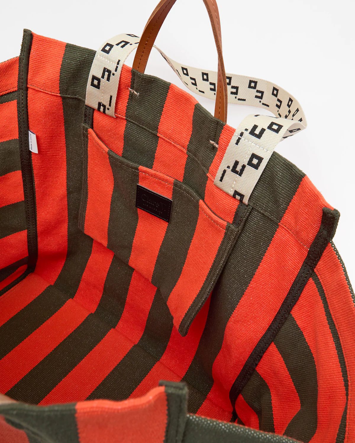 Red and black striped bag with a patterned strap on a white background