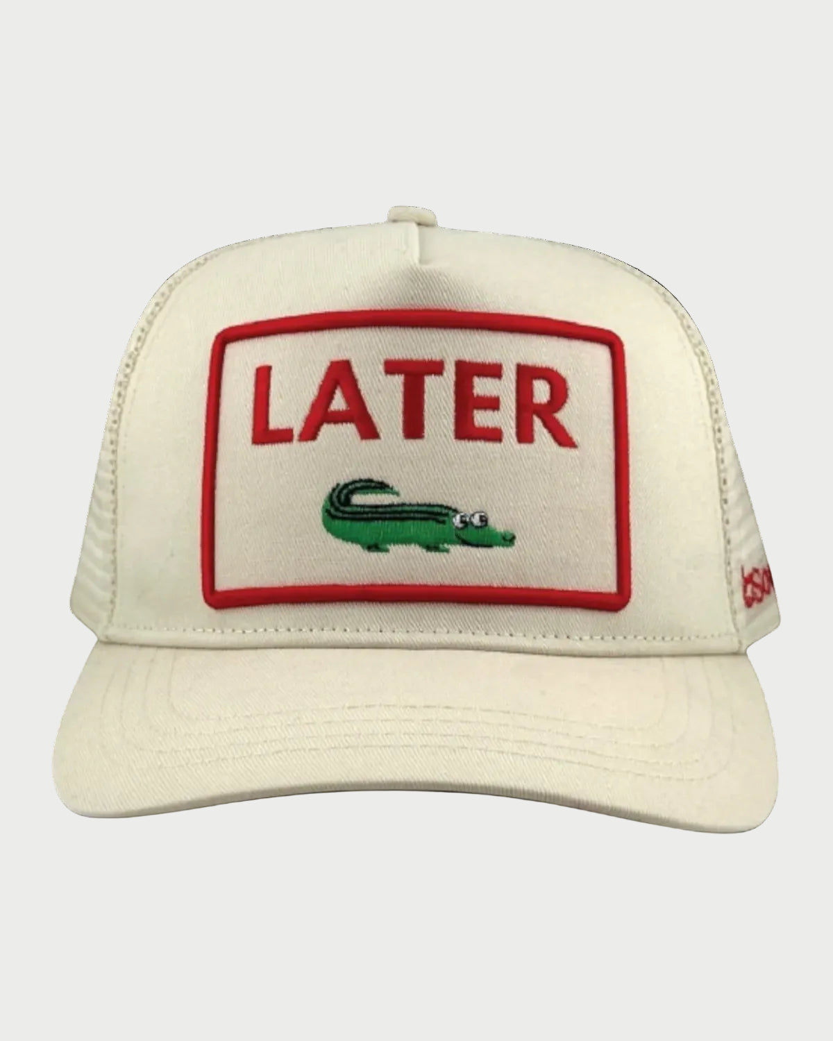The Soulbyrd Later Gator Ivory Trucker Hat features a cream snapback design with a red-trimmed embroidered patch that reads "LATER" in bold red above a googly-eyed green alligator—a standout accessory from Soulbyrd.