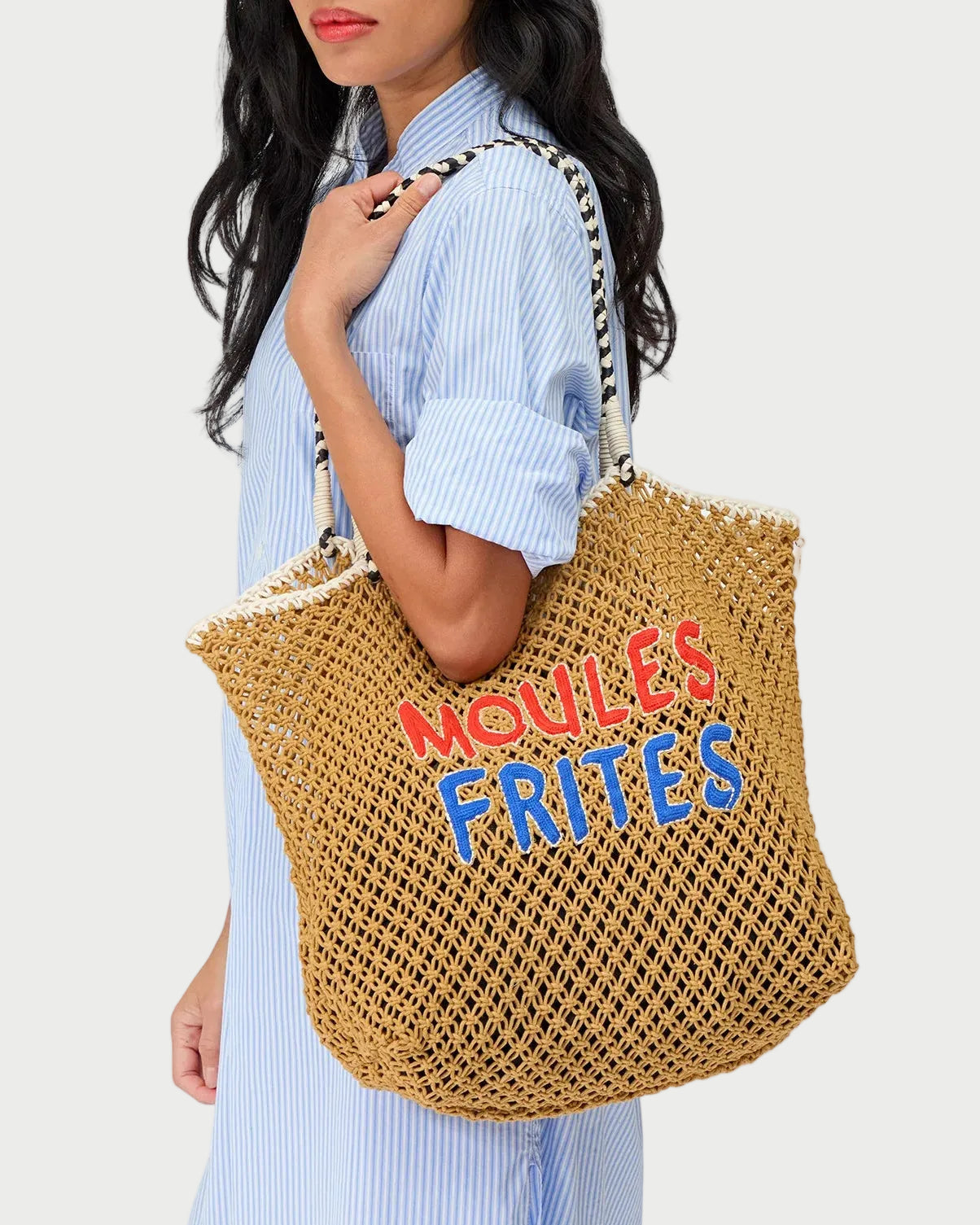 Woman holding a woven bag with colorful text against a white background