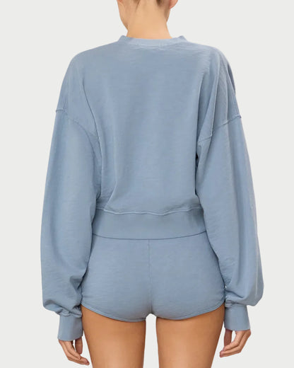 Person wearing a light blue sweatshirt and shorts set on a white background