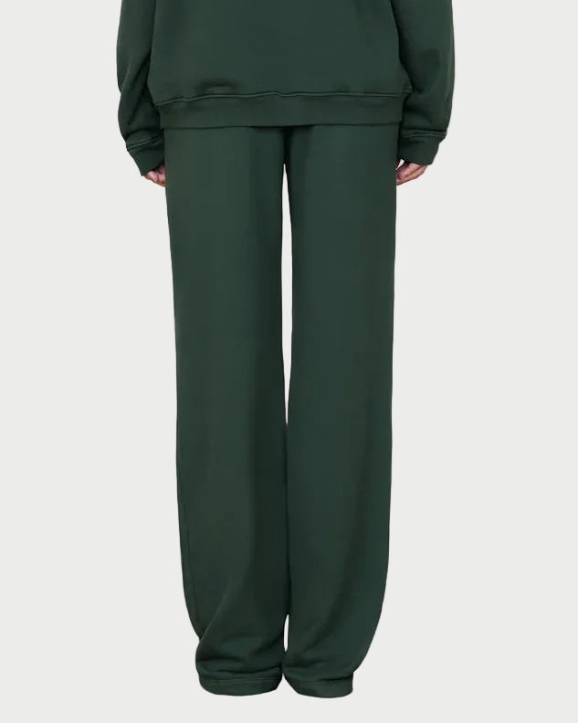 A person wearing Éterne Oversized Wide Leg Sweatpants in dark green stands against a plain light background, with only the lower part of their body visible.
