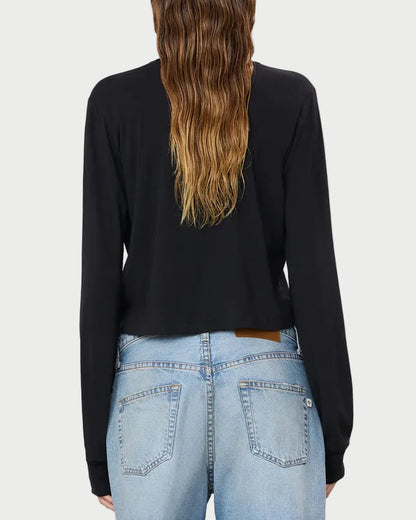 A person with long, wavy brown hair is shown from the back against a plain, light background, wearing the Éterne Long Sleeve Boxy Tee by Eterne in black—a soft cotton-modal blend—paired with light blue jeans.