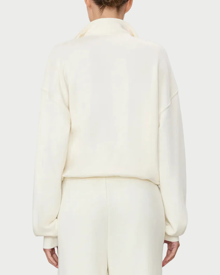 Person wearing a light-colored outfit on a plain background